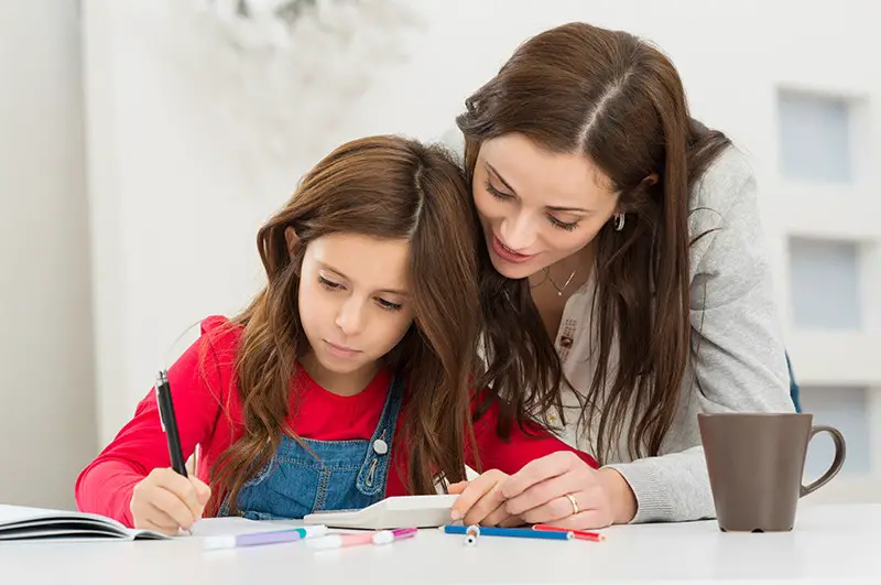 a mother helping her daughter to study