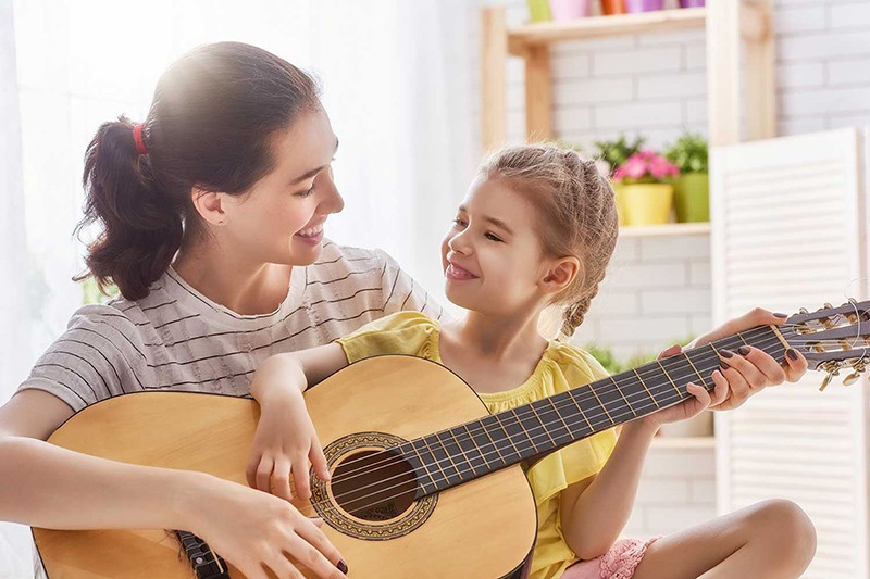 Why Music is Beneficial for Parents and Children a mother teaching her daughter to play the guitar