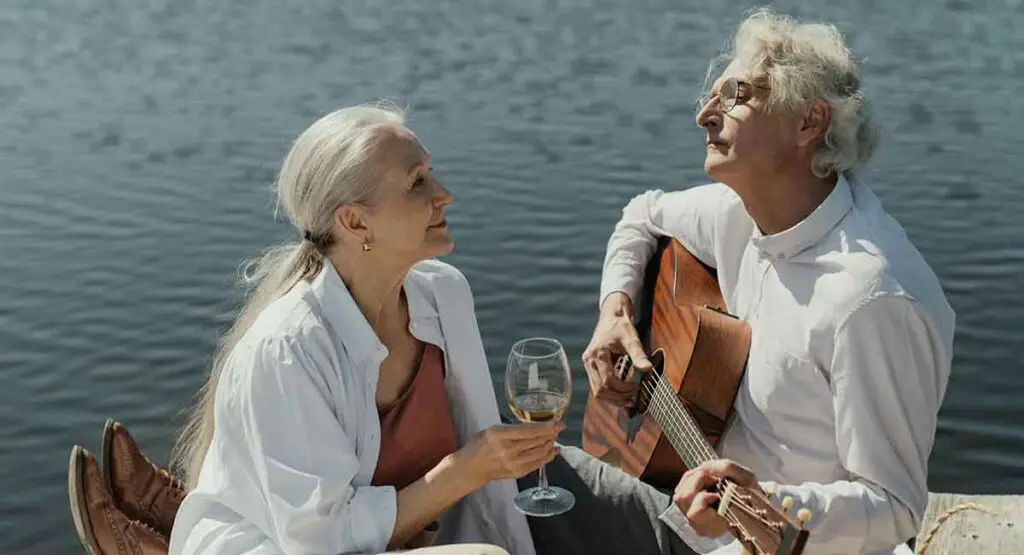Man playing guitar by the river with wife