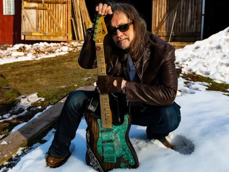 Jake E Lewis holding a green guitar