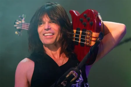 Rudy Sarzo with a guitar behind his head