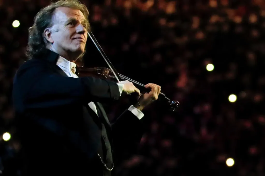 André Rieu smiling while playing the violin during a concert.