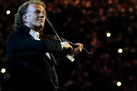 André Rieu smiling while playing the violin during a concert.