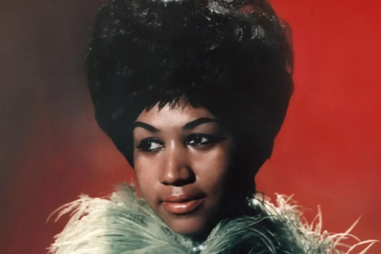 Portrait of Aretha Franklin wearing a green feathered outfit against a red background.