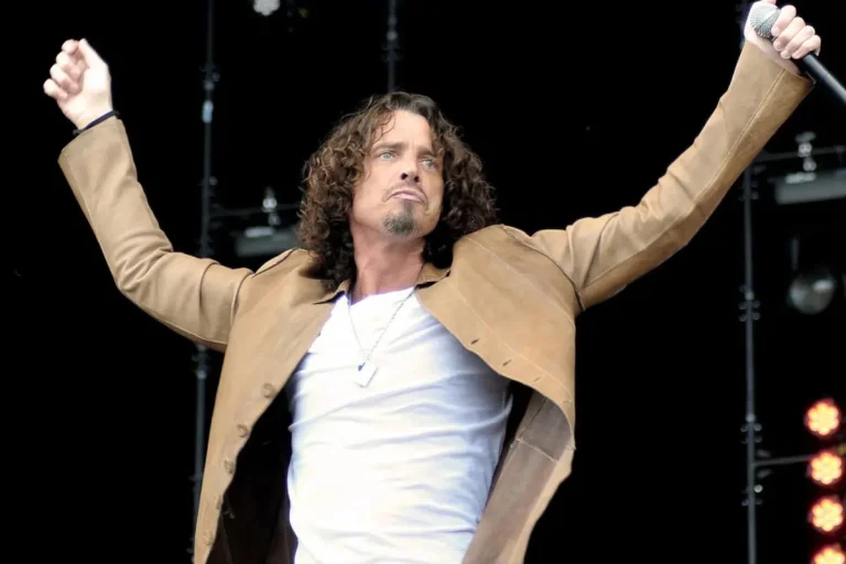 Chris Cornell stands at center stage with a hollow-body electric guitar, leaning into the microphone as he sings.