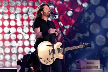 Dave Grohl onstage smiling and singing into a microphone.