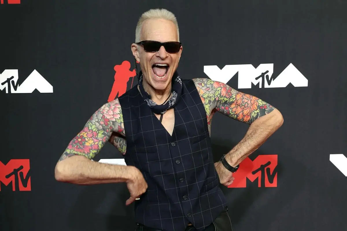 David Lee Roth posing at an MTV event wearing sunglasses and a sleeveless vest.