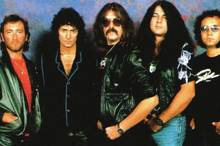 A Deep Blue band stands together against a studio backdrop, dressed in dark clothing and leather jackets.