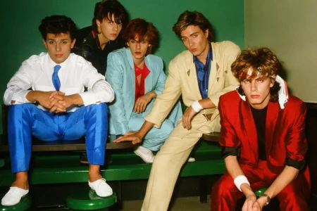 Duran Duran posing backstage in colorful 1980s outfits.