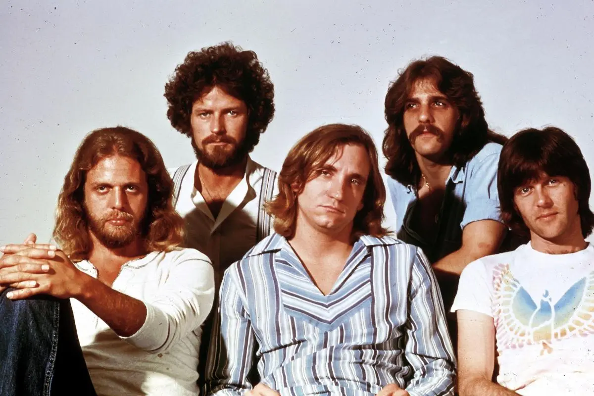 Eagle's band pose closely together for a studio portrait, dressed in casual 1970s-style clothing.