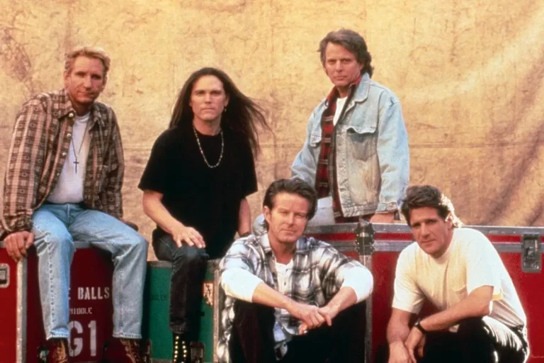 Eagles band posed together backstage in a classic group photo.