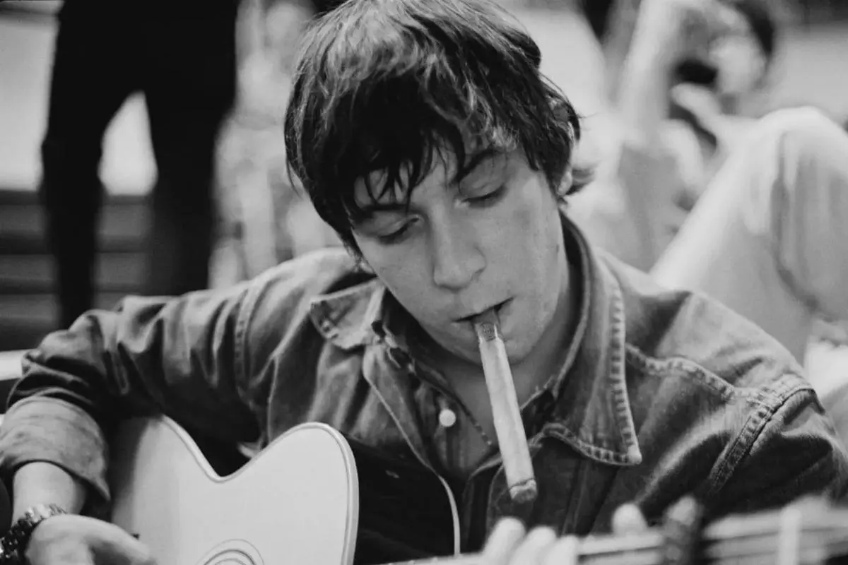 Eric Burdon (early career), playing acoustic guitar in a candid black-and-white photo