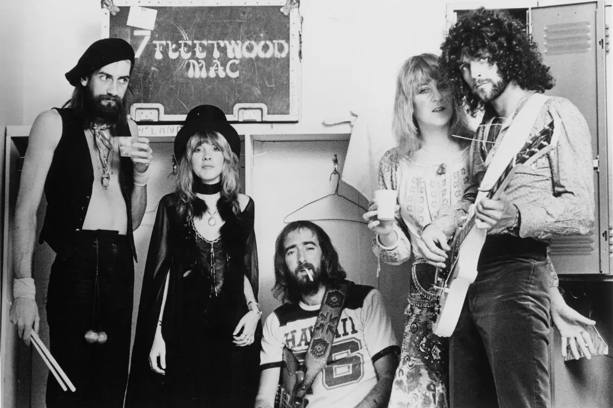 Fleetwood Mac posing backstage, including Stevie Nicks, Lindsey Buckingham, Mick Fleetwood, John McVie, and Christine McVie.