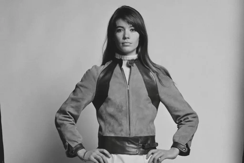 Françoise Hardy standing confidently with hands on hips.