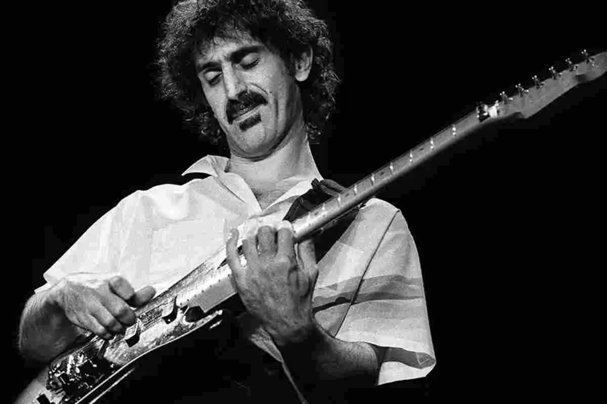 Eric Clapton playing electric guitar on stage with a Union Jack backdrop.