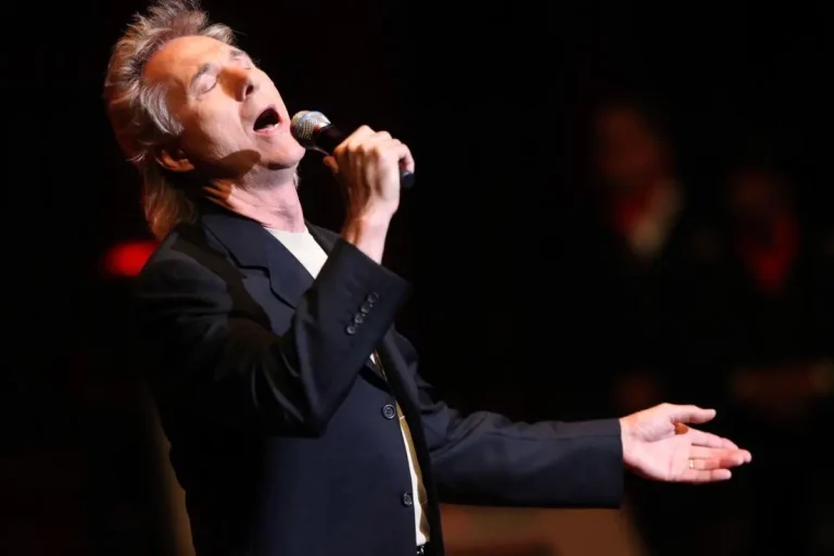 Gary Puckett performs passionately onstage, tilting his head back while holding a microphone and extending one arm outward.