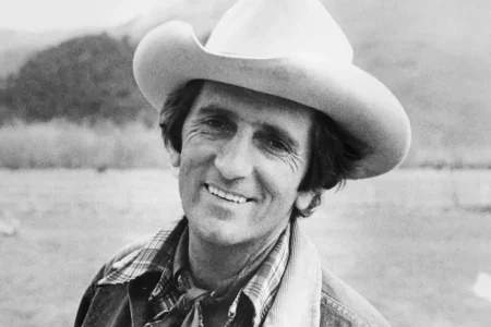 Harry Dean Stanton smiling outdoors in a black-and-white portrait, wearing a cowboy hat.