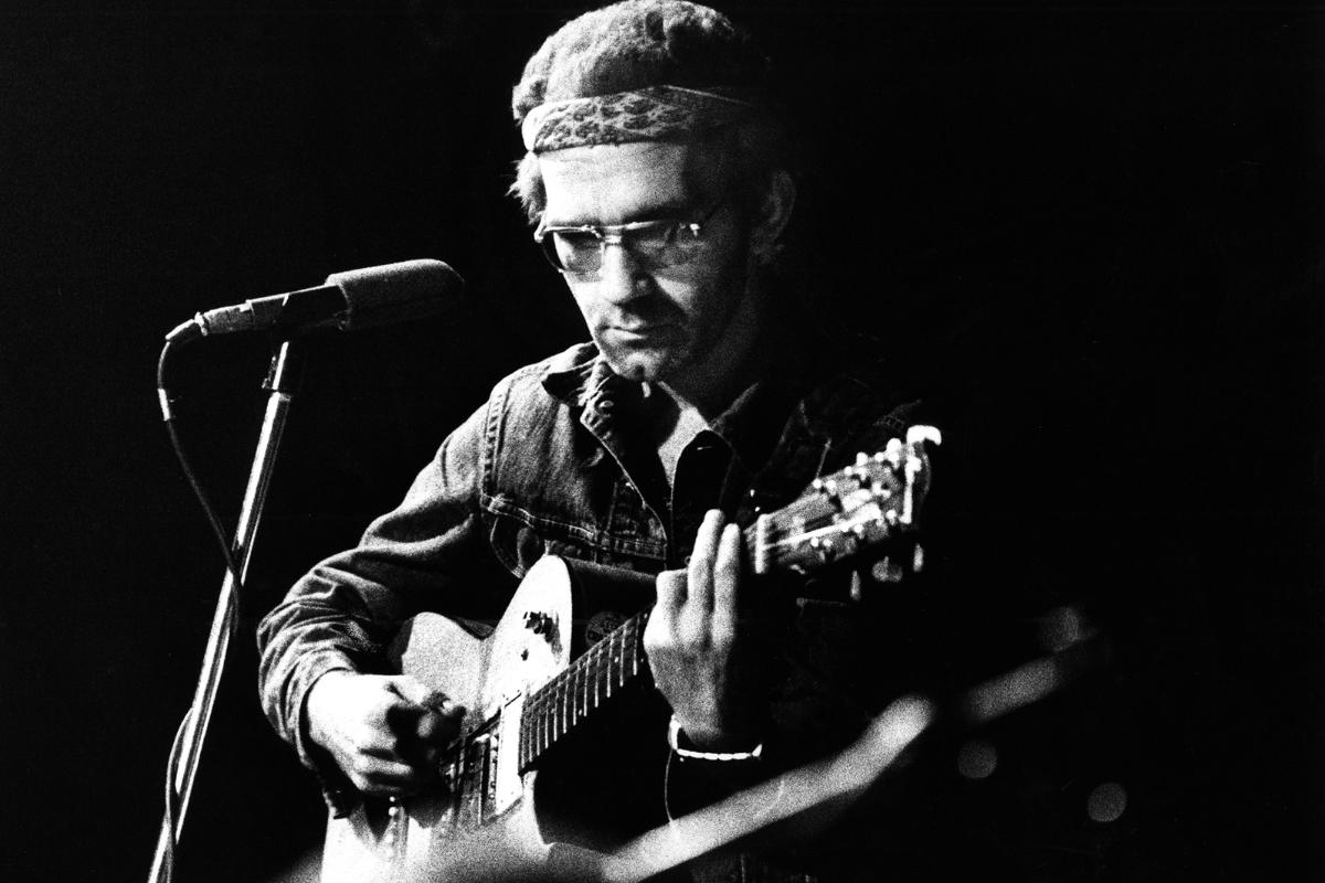 JJ Cale performs alone onstage.