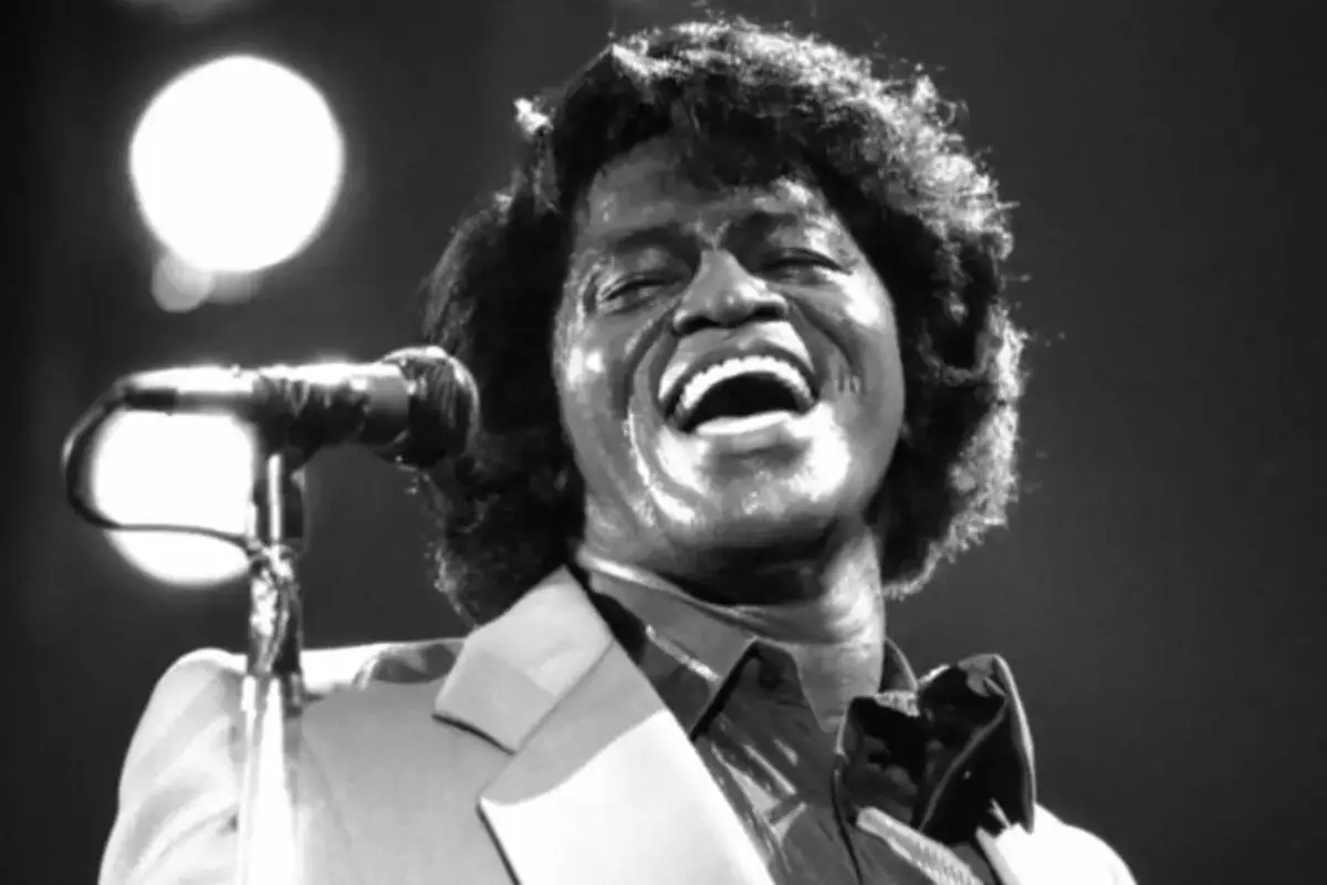 James Brown smiling mid-performance, captured in a high-energy concert moment.