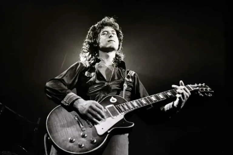 Jimmy Page: The Riff Architect Who Turned Rock Into a Religion Jimmy Page performing on stage with an electric guitar in a dramatic black-and-white concert photo.