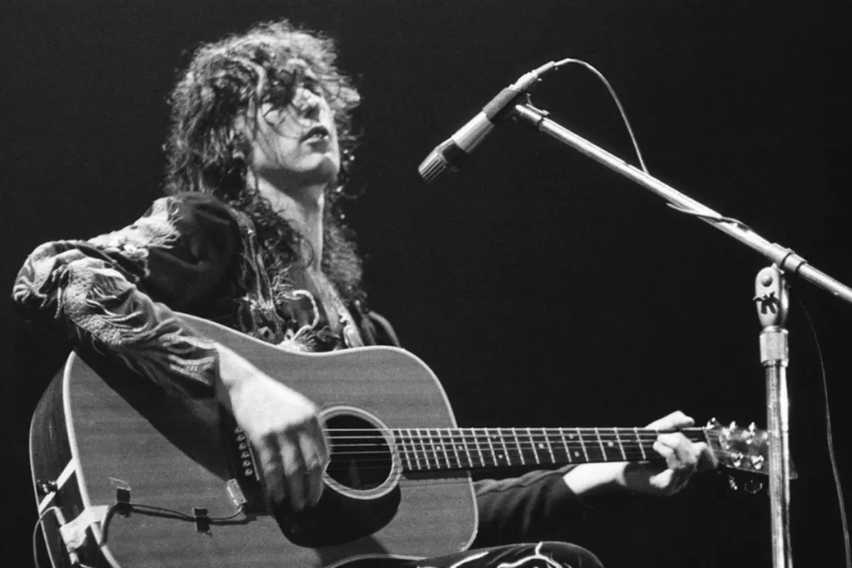 Jimmy singing and playing acoustic guitar into a microphone during a live performance.
