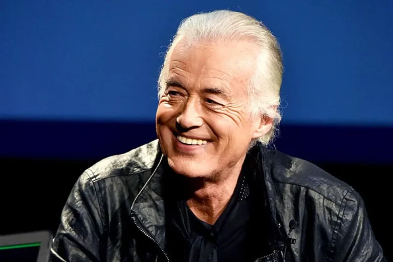 Jimmy Page again smiling, with his silver hair neatly back, wearing a black leather jacket.