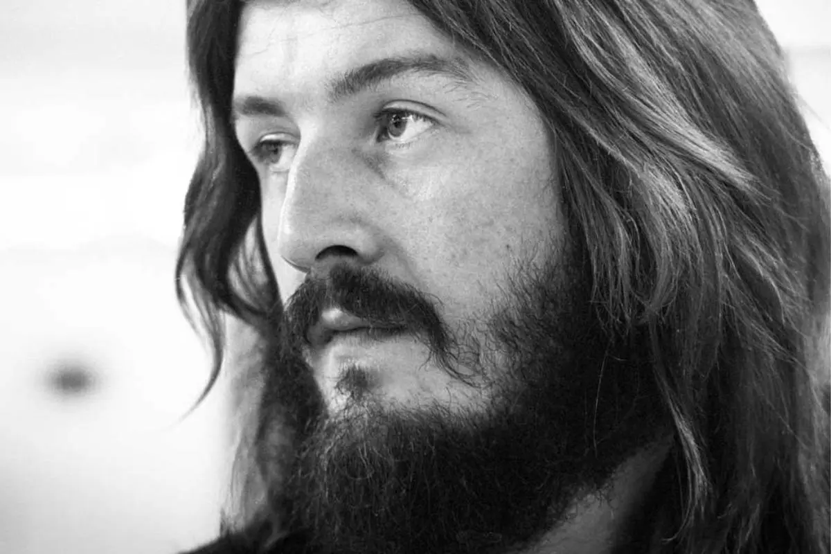 John Bonham with long hair and a full beard, looking thoughtfully to the side.