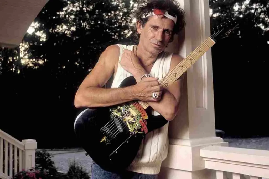 The “Keith Burst” Mystery: How One ’59 Les Paul Haunted the Rolling Stones Keith Richards holding an electric guitar, wearing a sleeveless shirt and headband.