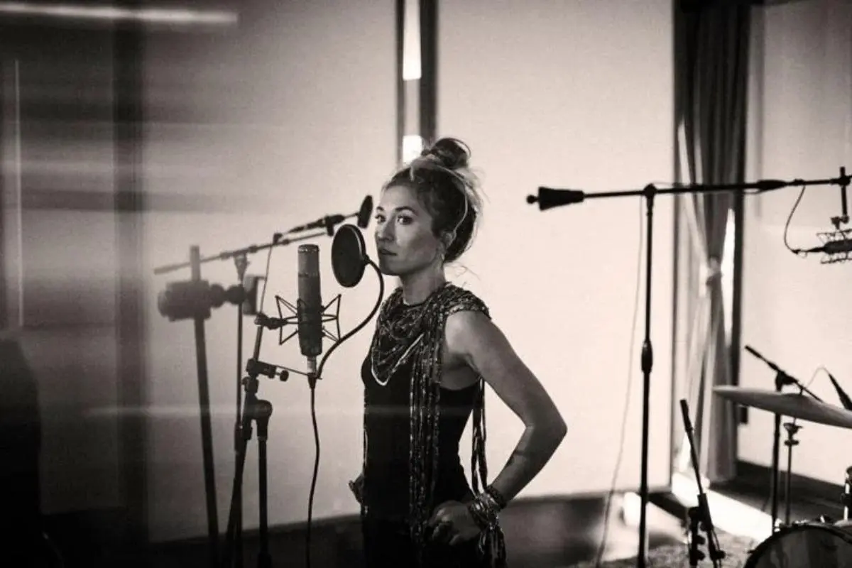 Lauren Daigle standing in a recording studio beside a microphone in a black-and-white photo.