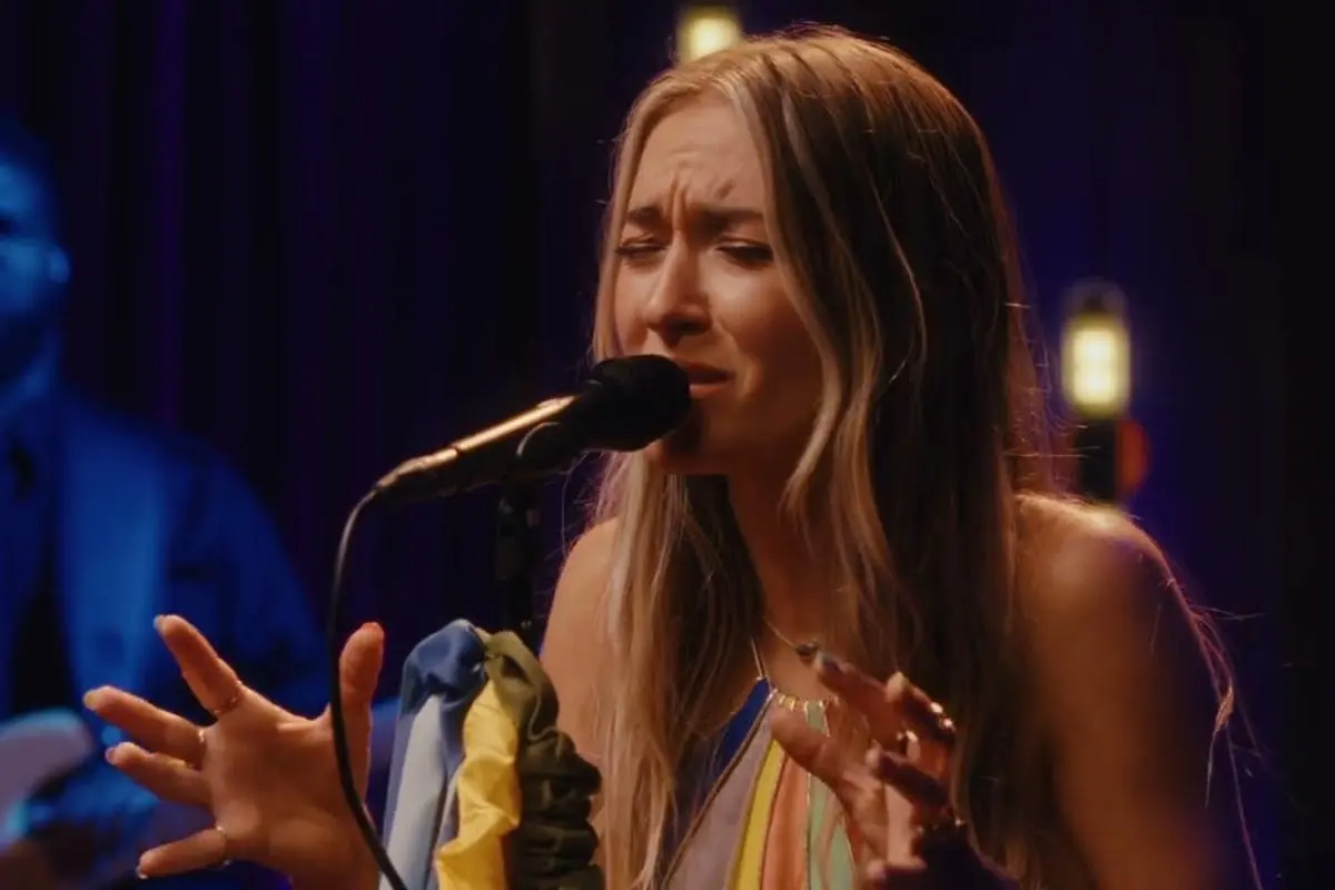 Lauren Daigle singing passionately into a microphone during a live performance.