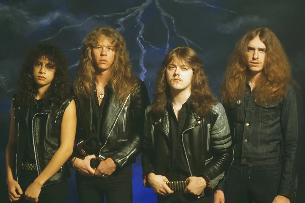 Metallica band standing shoulder to shoulder in leather jackets against a dramatic, storm-like backdrop, conveying intensity and a classic heavy metal image.