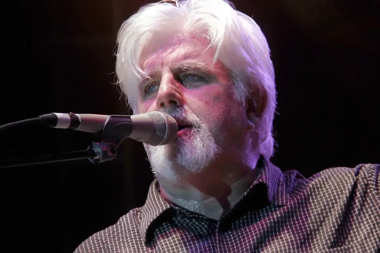 Close-up of Michael McDonald singing into a microphone onstage.