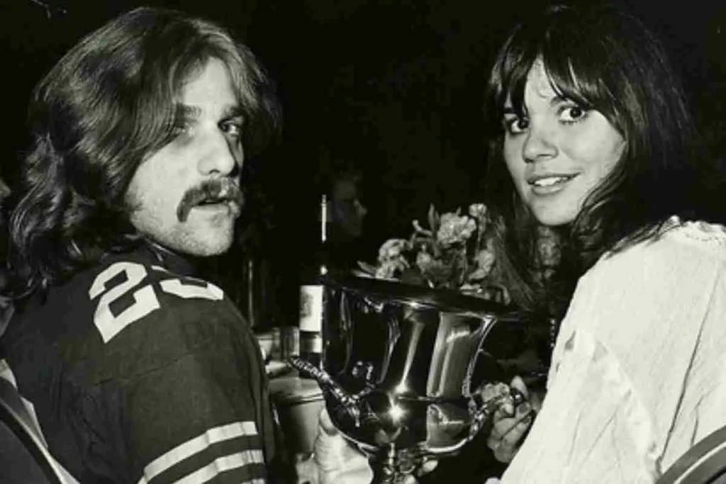 Mick Jagger and Linda Ronstadt holding a trophy together in a black-and-white photo.