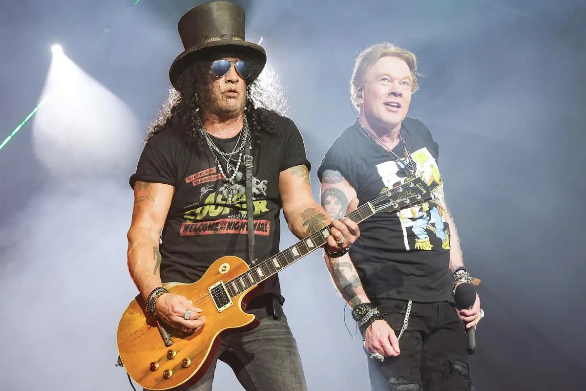 Nine Inch Nails performing live, guitarists and vocalist under bright stage lights.