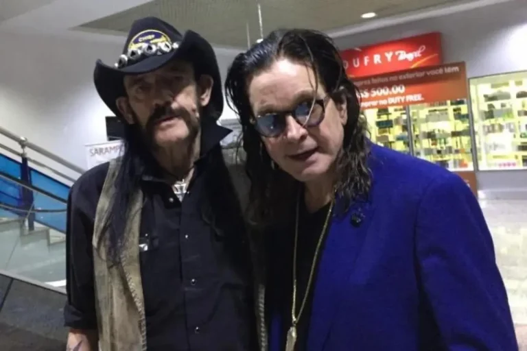 Ozzy Osbourne and Lemmy Kilmister stand close together indoors, both dressed in dark clothing, posing casually for a candid photo.