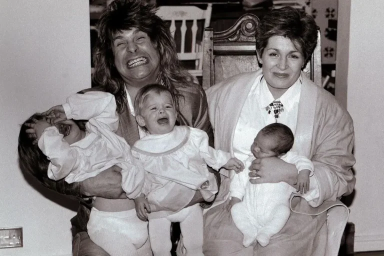 Ozzy and Sharon making an exaggerated grin while holding three infants.
