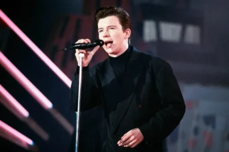 Young Rick Astley singing into a microphone during an early live performance.