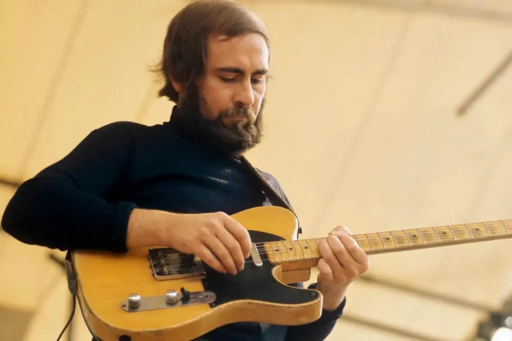 Roy Buchanan plays a worn yellow electric guitar, his eyes lowered as he picks the strings.