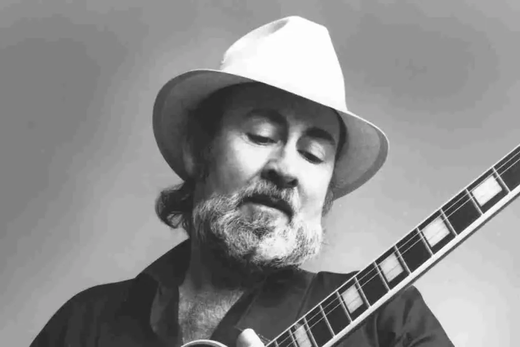 Roy Buchanan playing guitar in a black-and-white portrait, wearing a light-colored hat.