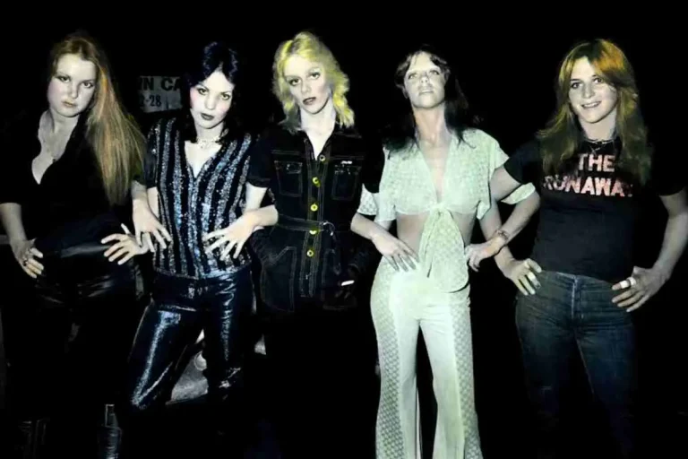 The Runaways standing side by side in a nighttime group photo, wearing stage and street outfits.