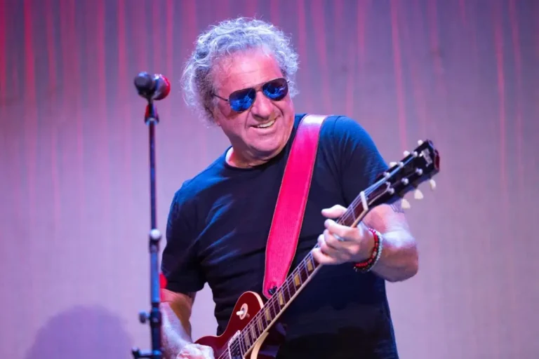 Sammy Hagar playing electric guitar on stage while wearing sunglasses.