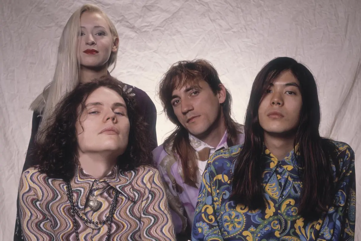 The Smashing Pumpkins posed in a studio portrait, wearing colorful, retro-inspired clothing.