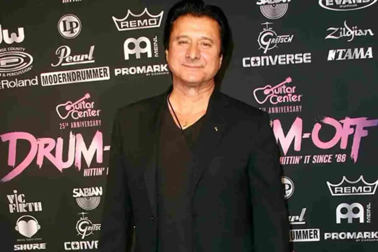 Steve Perry posing at a red carpet event, wearing a black jacket and shirt.