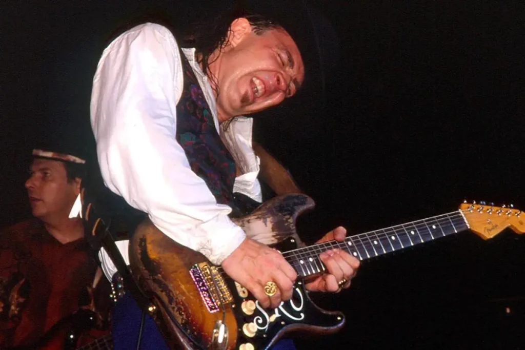 Stevie Ray Vaughan playing electric guitar passionately during a live performance.