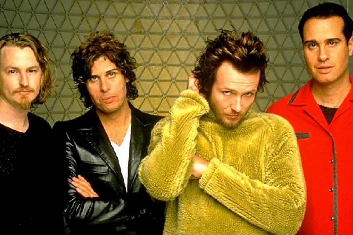 Stone Temple Pilots posing in front of a textured wall, wearing leather, knit, and brightly colored jackets.