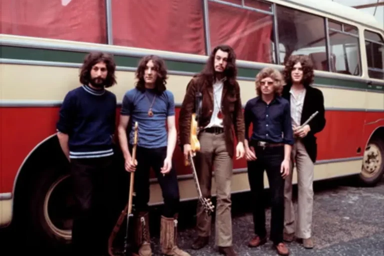 Supertramp band members posing outdoors in front of a tour bus.