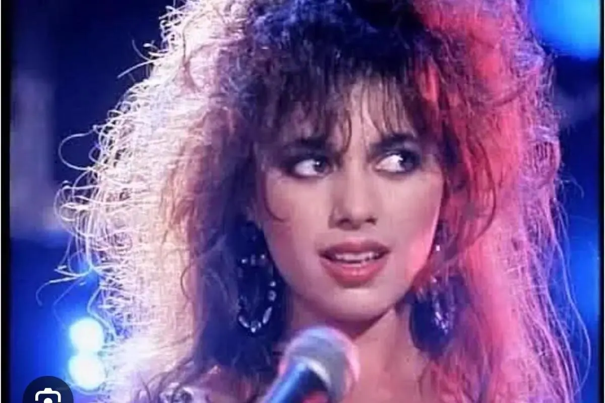 Susanna Hoffs singing into a microphone during a live performance.