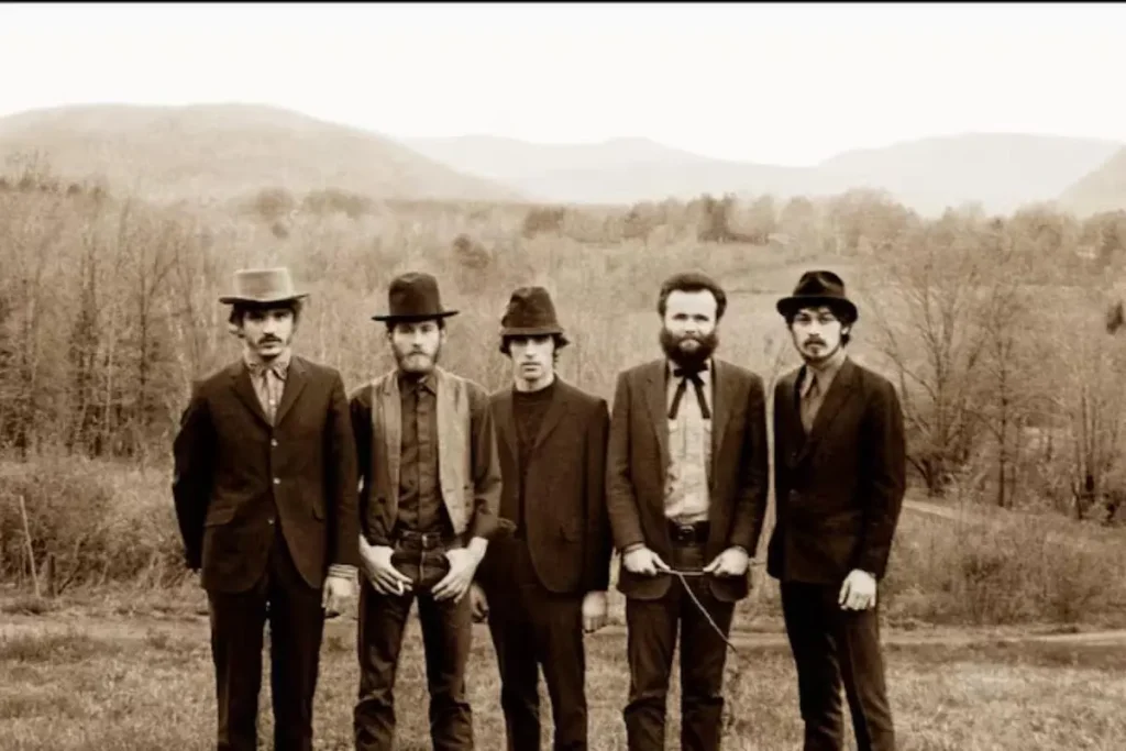 The Band posing outdoors in vintage suits with a rural landscape in the background.