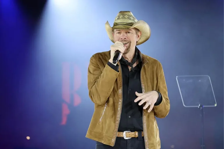 Toby Keith’s “O Come All Ye Faithful”: The Backstory Behind His Big, Bold Carol Toby Keith performs onstage wearing a tan cowboy hat and brown jacket.
