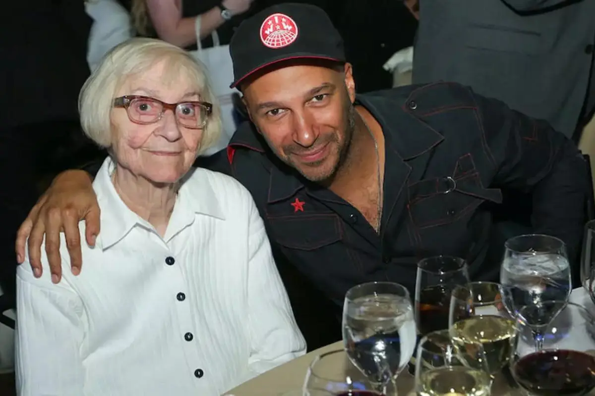 Mary Morello and Tom Morello sit close together at a dinner table, smiling toward the camera with several glasses of wine and water arranged in front of them.